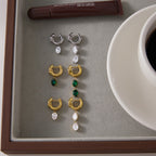Clear and green earring pairs displayed on a tray