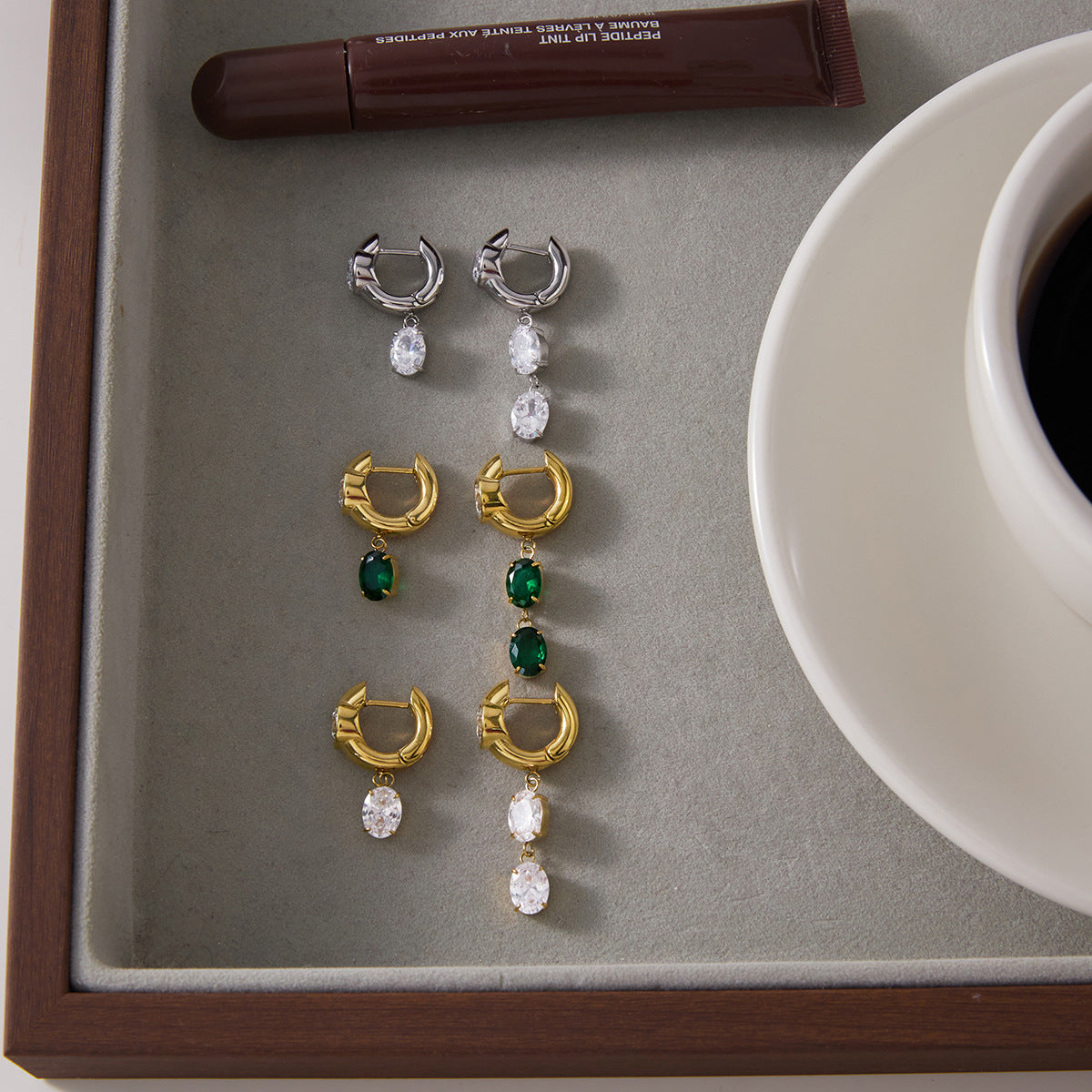 Clear and green earring pairs displayed on a tray