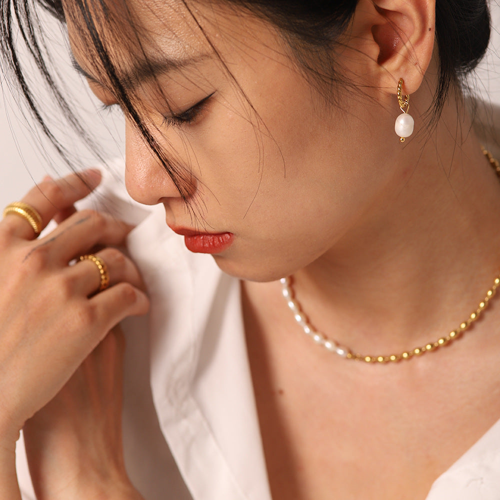 Model wearing twisted gold plated freshwater pearl drop hoops