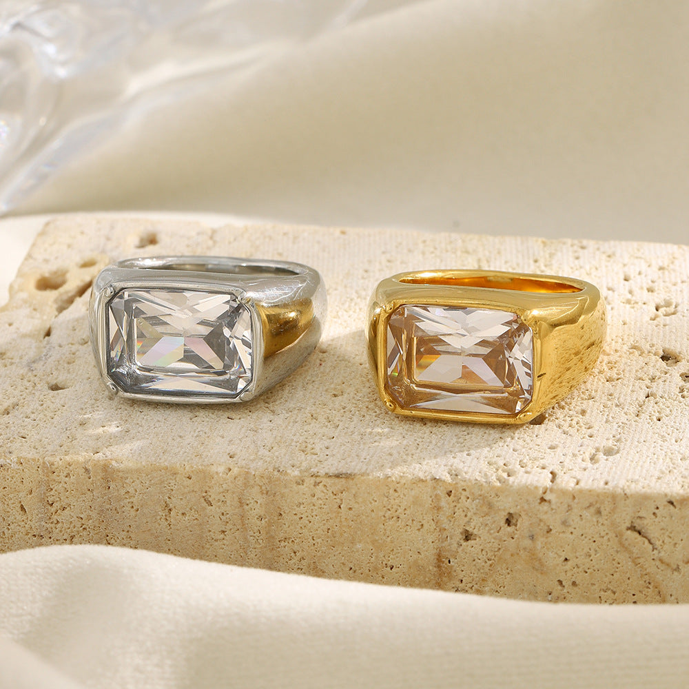 gold and silver rectangular clear stone rings on a stone display
