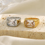gold and silver rectangular clear stone rings on a stone display
