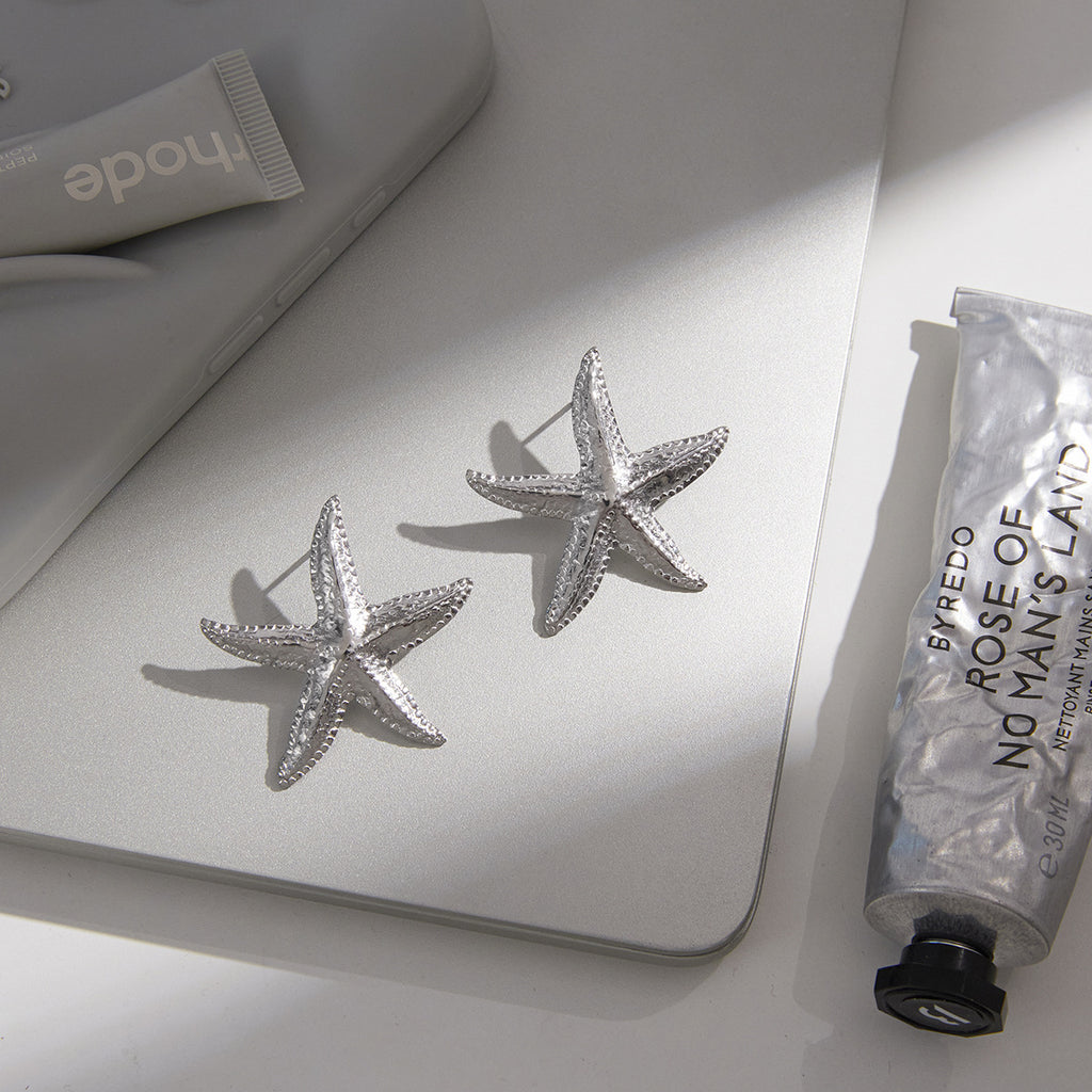 pair of silver-finish textured starfish earrings on a desk
