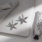 pair of silver-finish textured starfish earrings on a desk