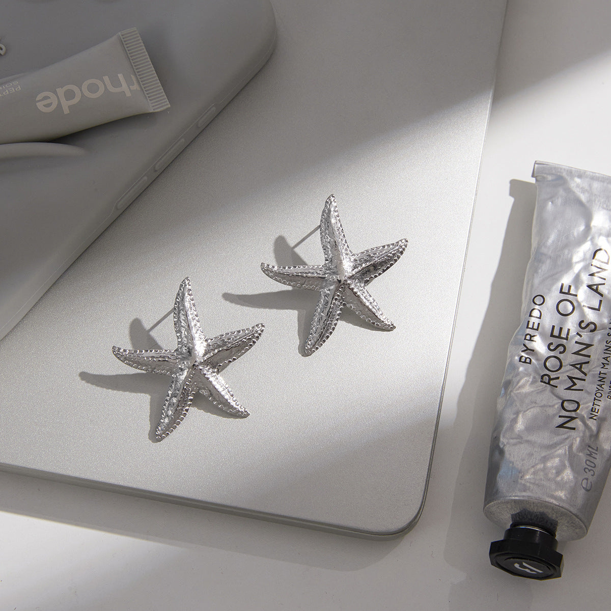 pair of silver-finish textured starfish earrings on a desk