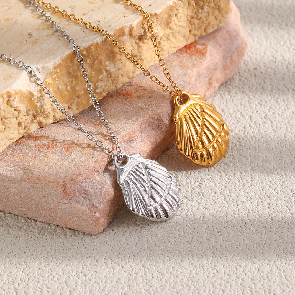 Gold and silver tone scallop shell necklaces displayed on stone