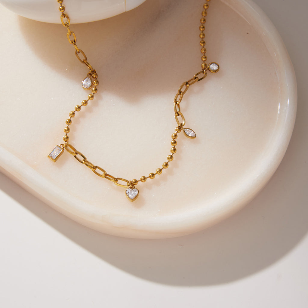 Bead and elongated-link sections with clear charms on a tray