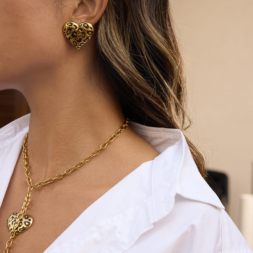 Heart necklace worn alongside an earring reference from the same visual theme