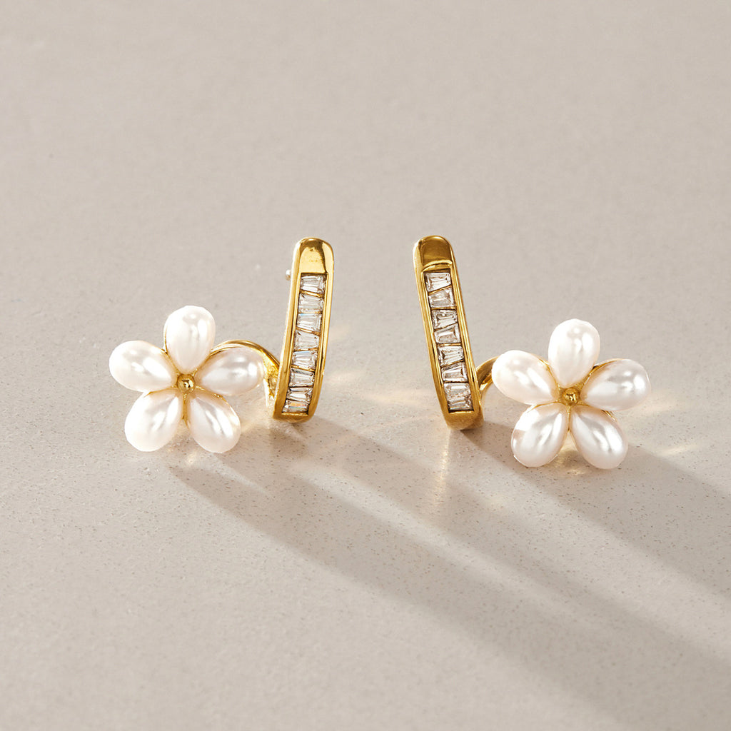 Pair of white resin pearl flower earrings on a surface