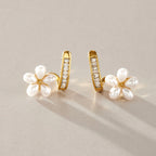 Pair of white resin pearl flower earrings on a surface