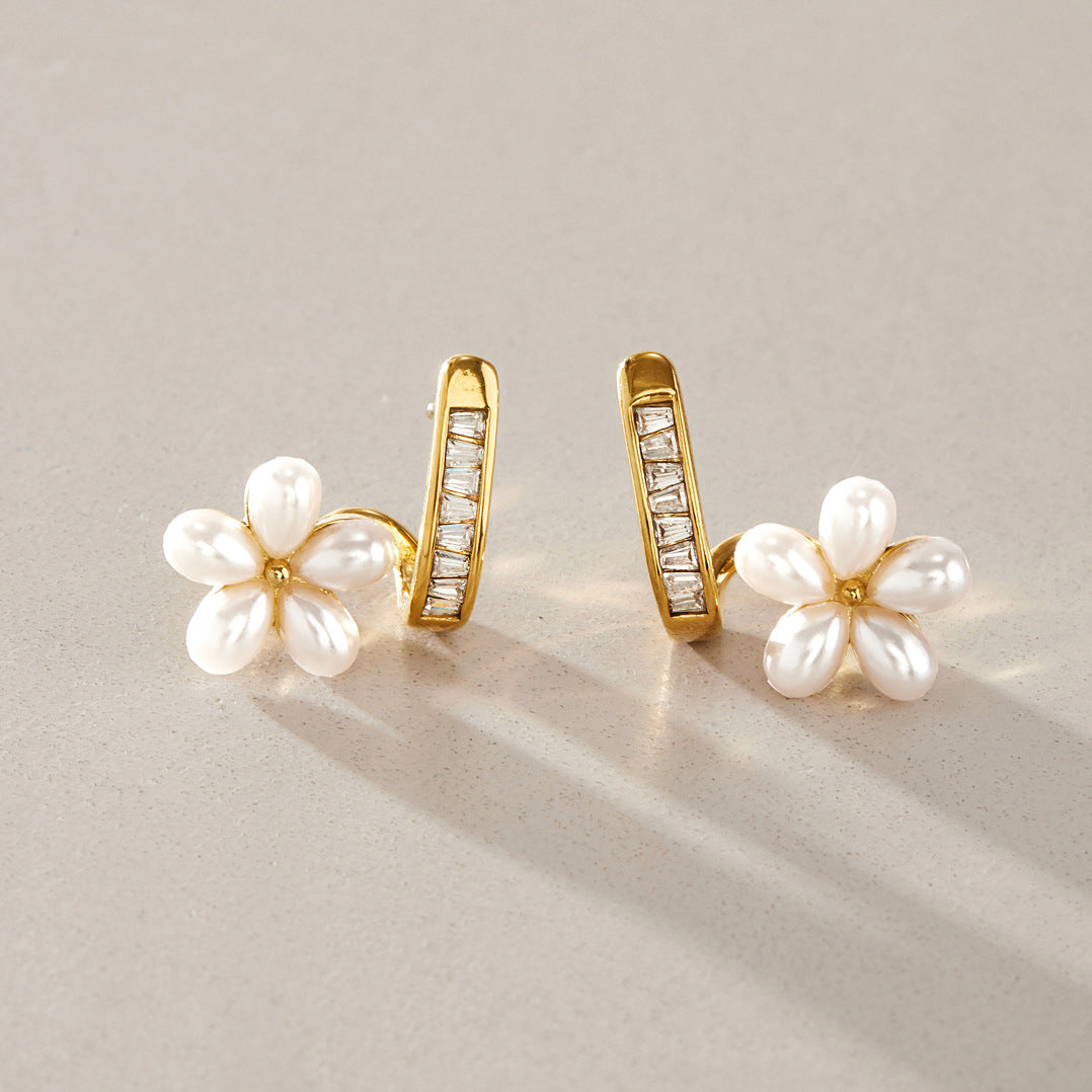 Pair of white resin pearl flower earrings on a surface