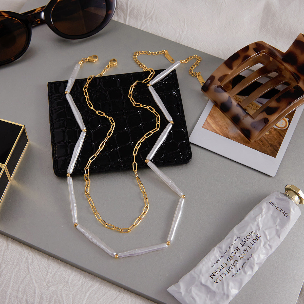 Both necklaces laid out beside accessories