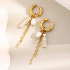 asymmetric pearl-bead and chain earrings arranged on a stone surface