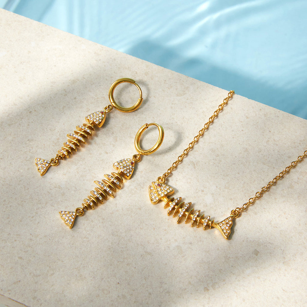 Fish necklace and earrings beside a pool