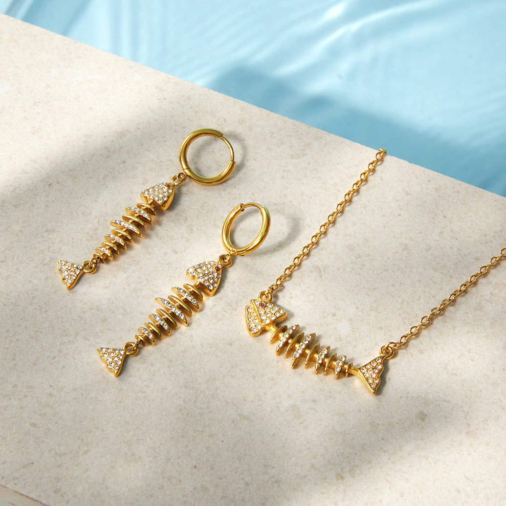 Fish necklace and earrings beside a pool