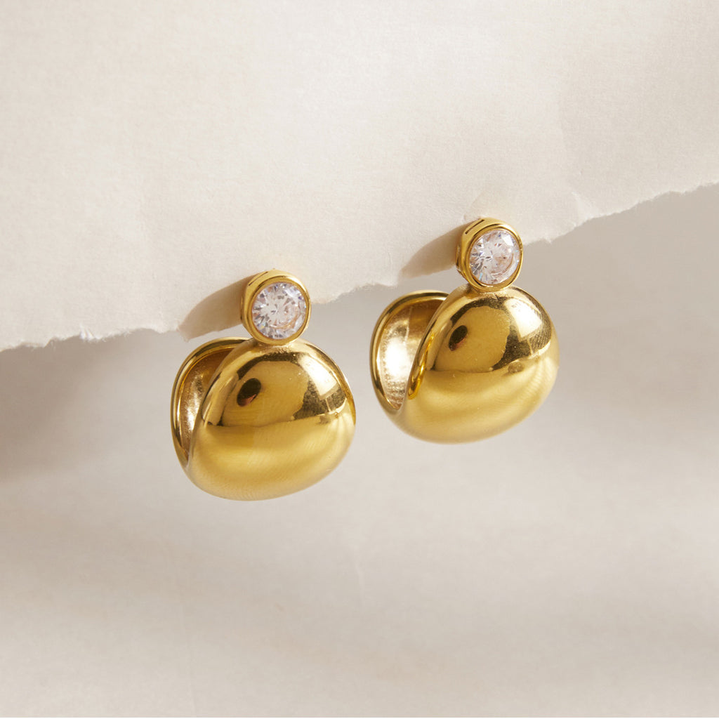 Pair of gold tone domed studs on a pale surface