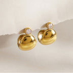 Pair of gold tone domed studs on a pale surface