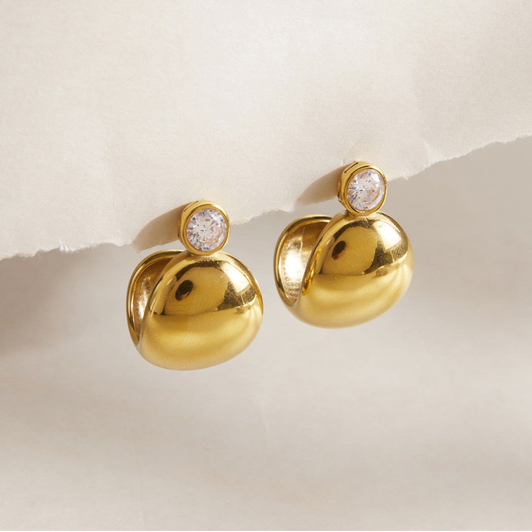 Pair of gold tone domed studs on a pale surface