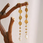 gold plated textured medallion pearl drop earrings hanging from a branch