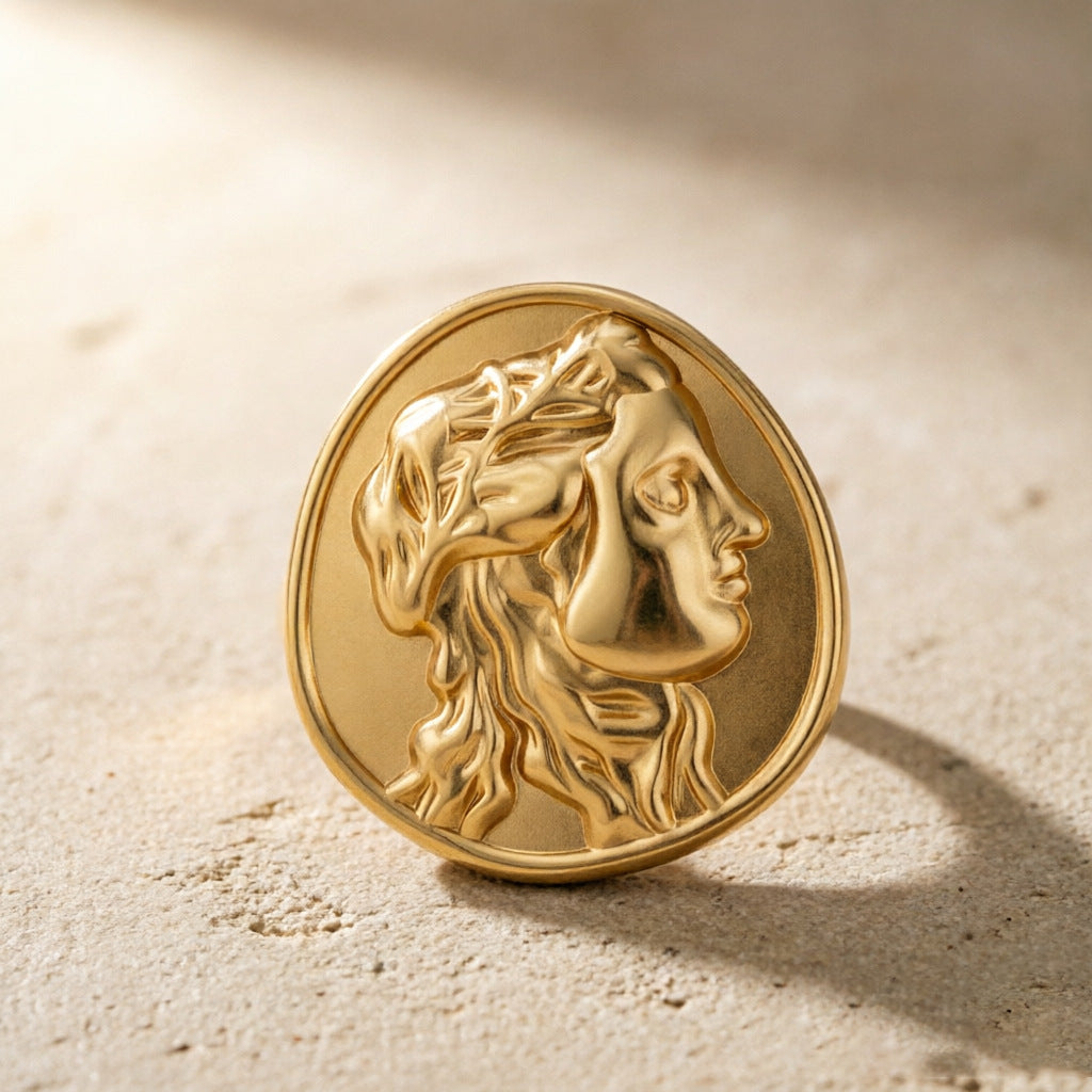 Gold tone portrait medallion ring standing on a pale surface
