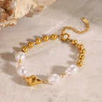 Gold ball and irregular white bead bracelet on a stone display