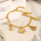 Gold Plated 316L Stainless Steel Coastal Charm Bracelet — charms and clasp on pale stone