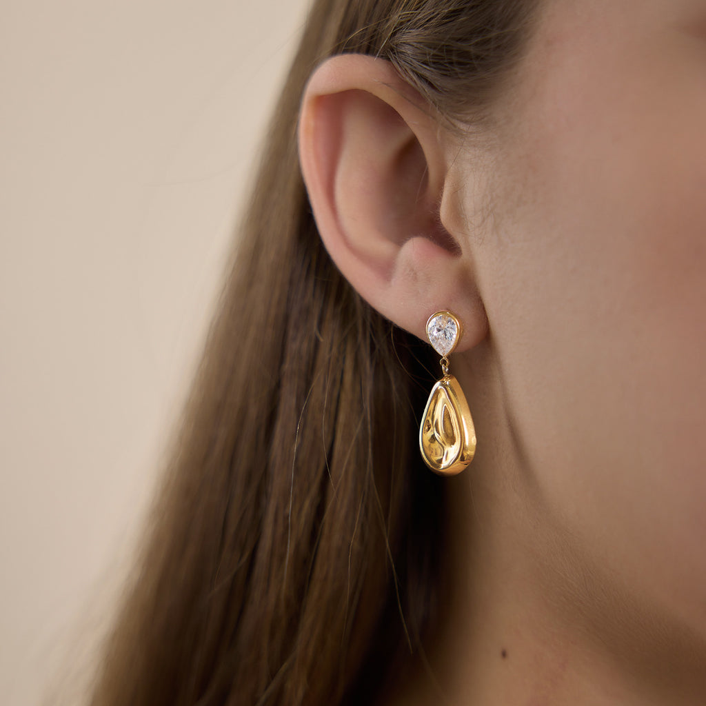Side view of polished teardrop earring worn on an ear