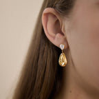 Side view of polished teardrop earring worn on an ear