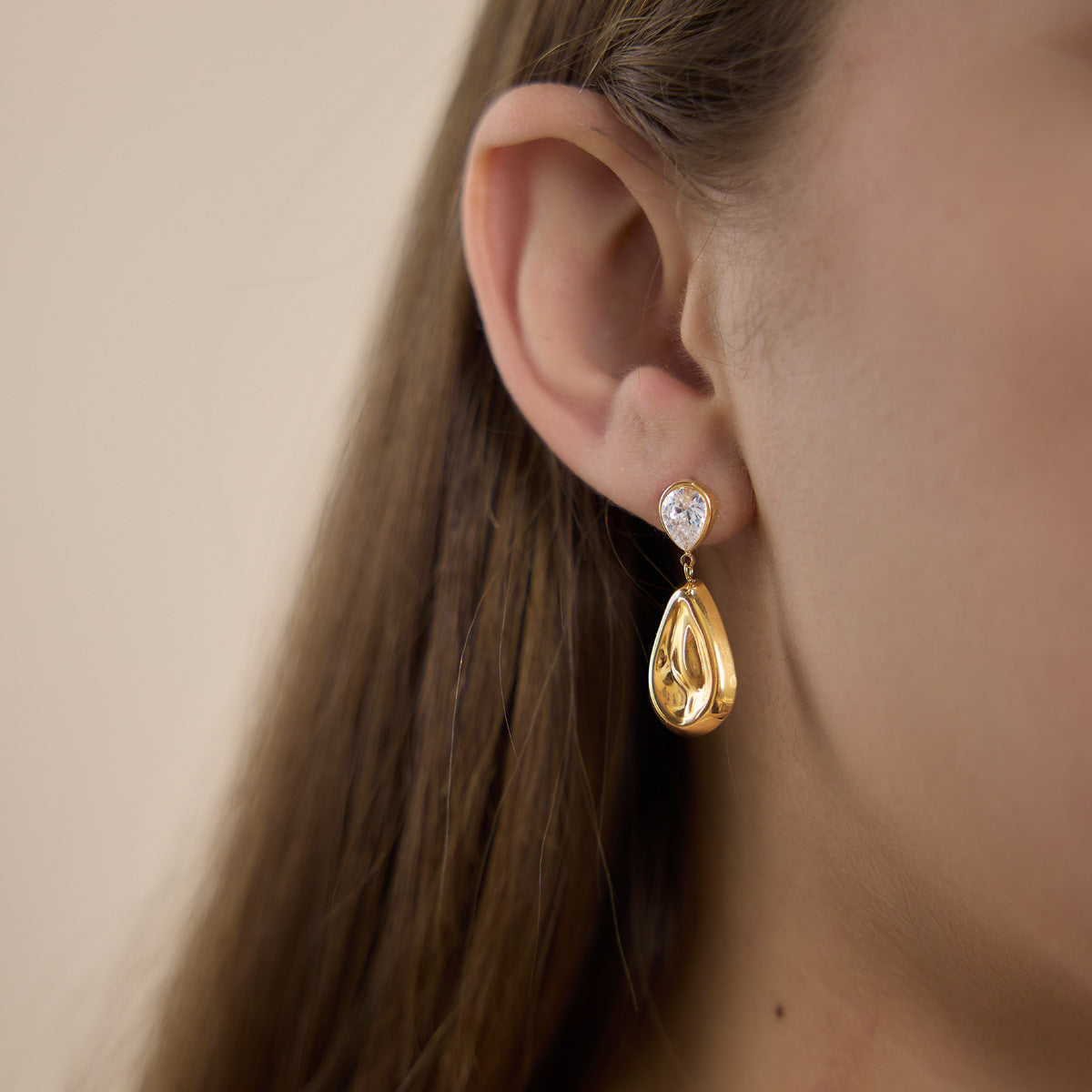Side view of polished teardrop earring worn on an ear