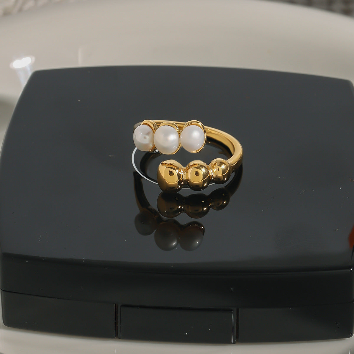 Gold plated white bead and ball open ring in a styled display
