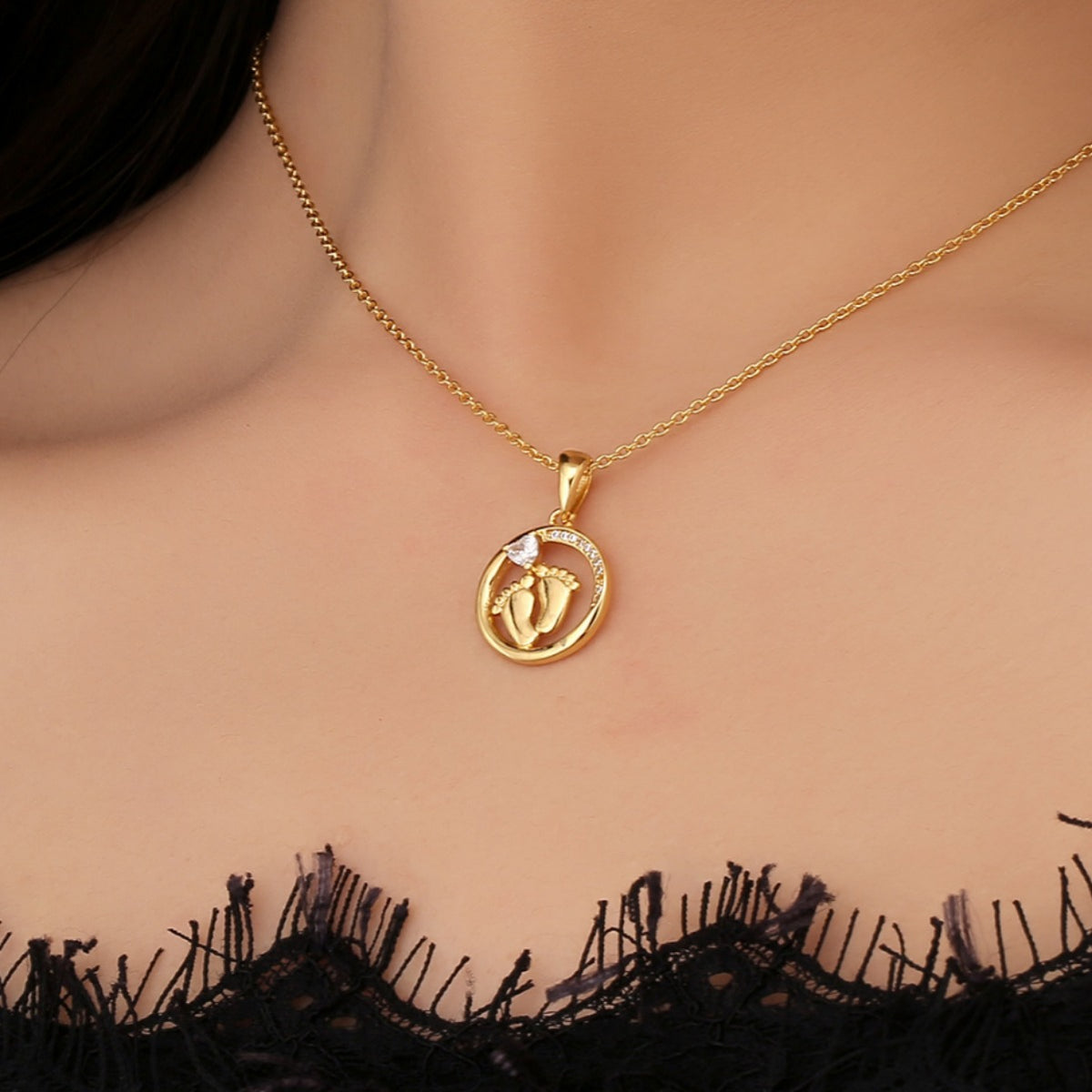 gold plated footprint pendant necklace worn at the collarbone