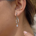 silver-finish geometric link clear-stone drop earring worn on ear