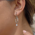 silver-finish geometric link clear-stone drop earring worn on ear