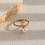 pearl-look bead ring with clear stone band displayed on pale texture