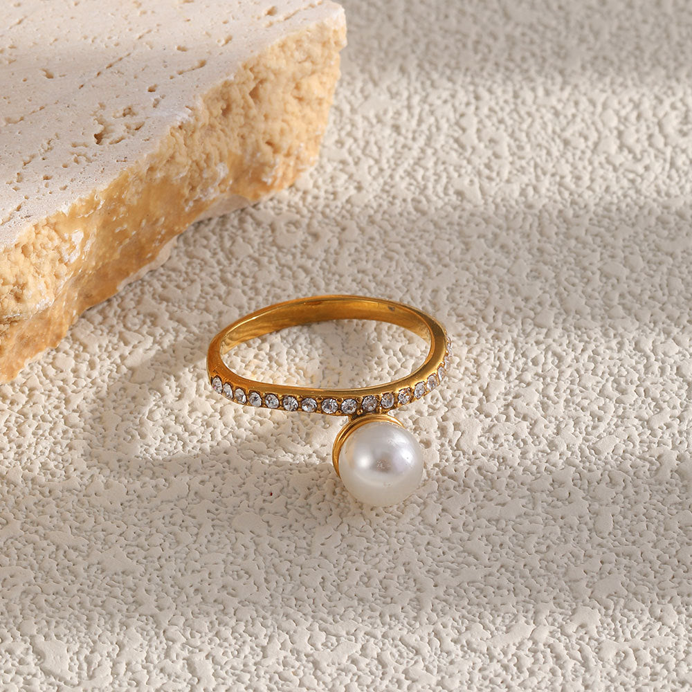 pearl-look bead ring with clear stone band displayed on pale texture