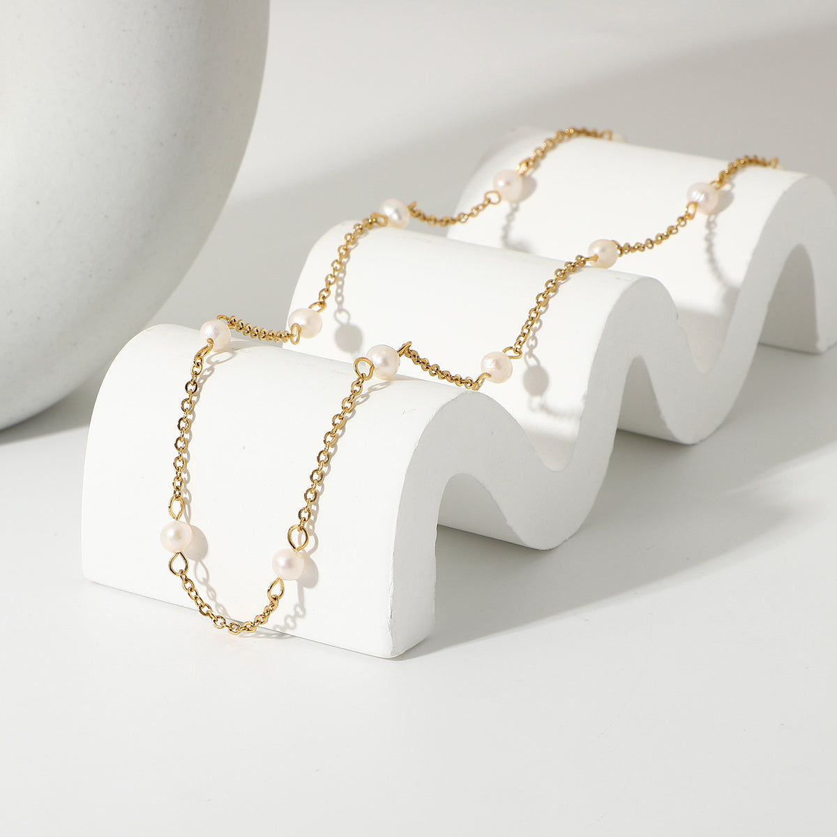 Freshwater pearl station necklace draped across a white stand