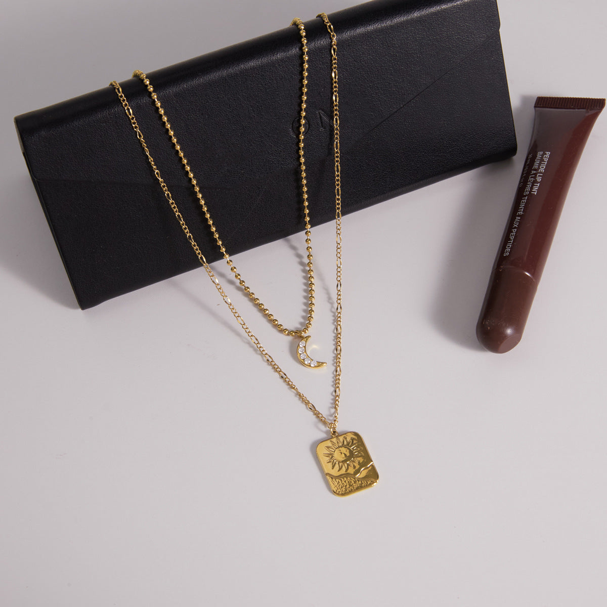 Layered pendant necklace displayed on a black accessory