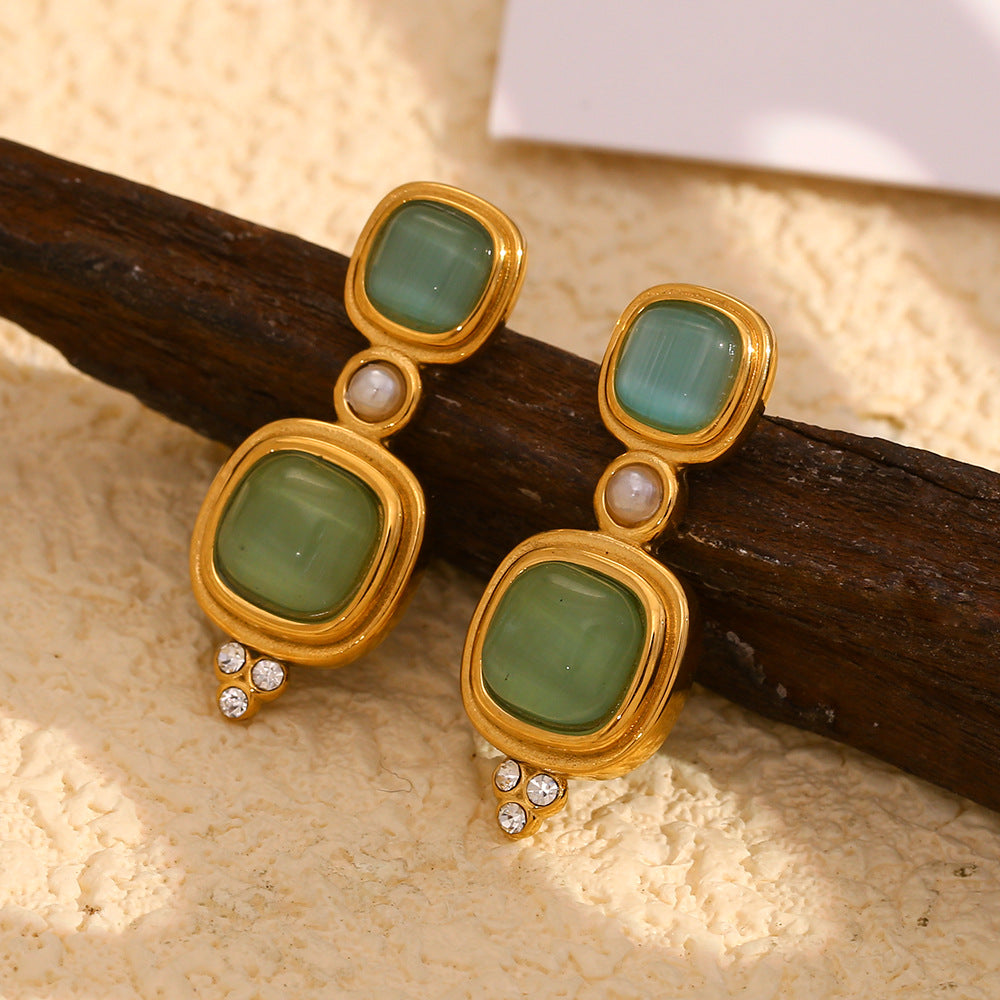 gold plated green cabochon drop earrings styled against dark wood