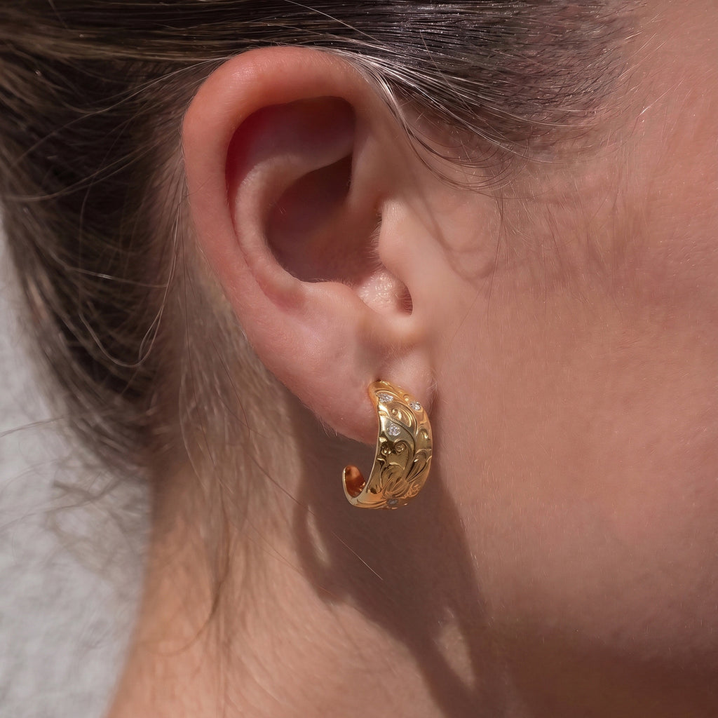 Tapered scroll hoop with clear accents worn on an ear