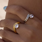 Gold tone and silver tone wavy solitaire rings worn together