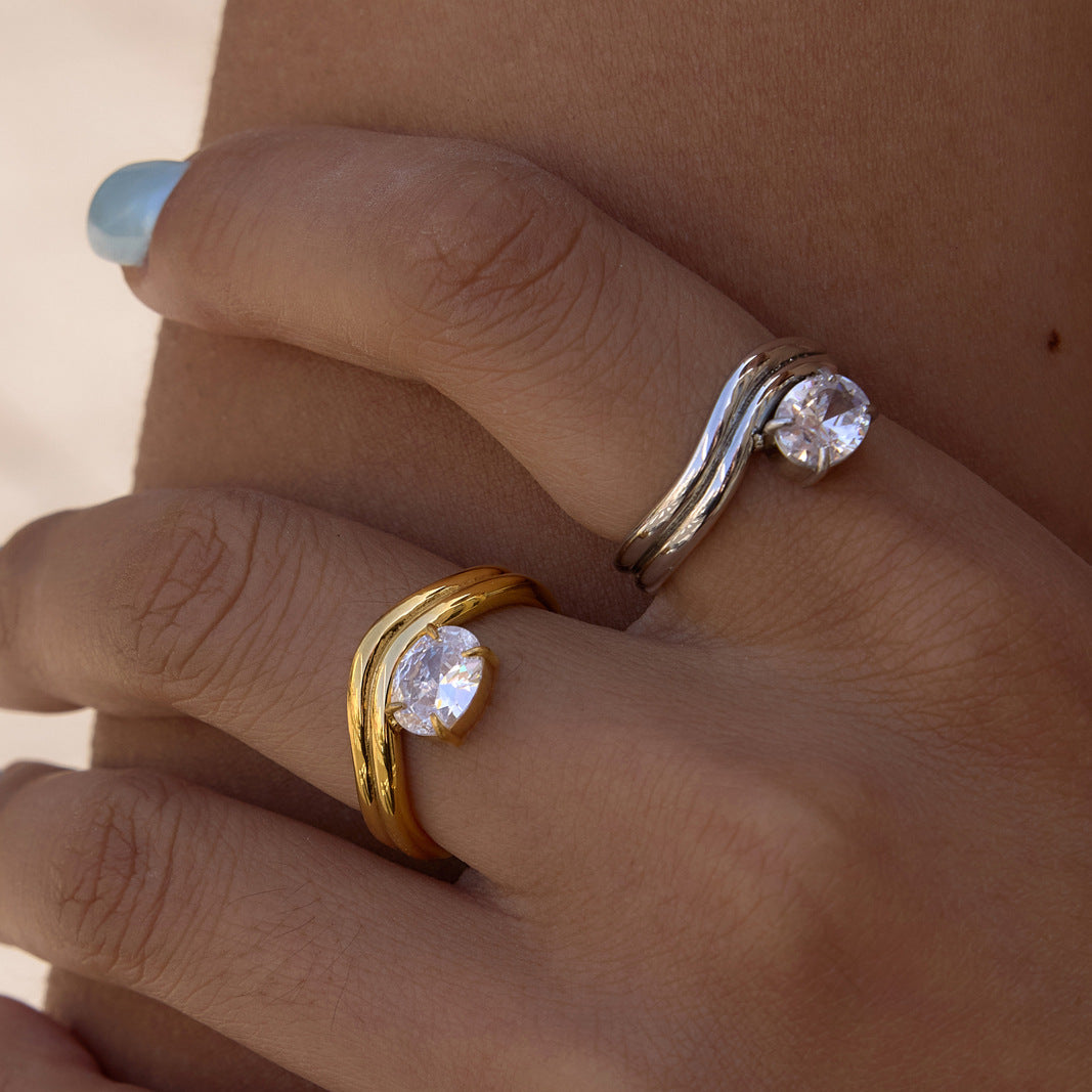 Gold tone and silver tone wavy solitaire rings worn together