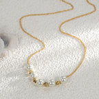 gold plated shell pearl necklace arranged on textured fabric