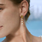 Gold-tone triple-bezel drop earring worn beside the face