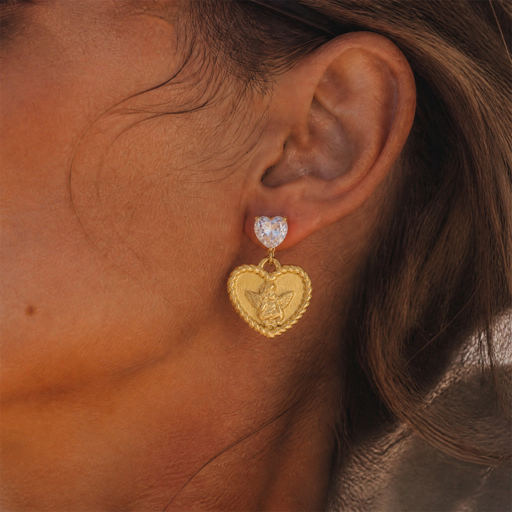 Gold tone angel heart earring shown on the ear