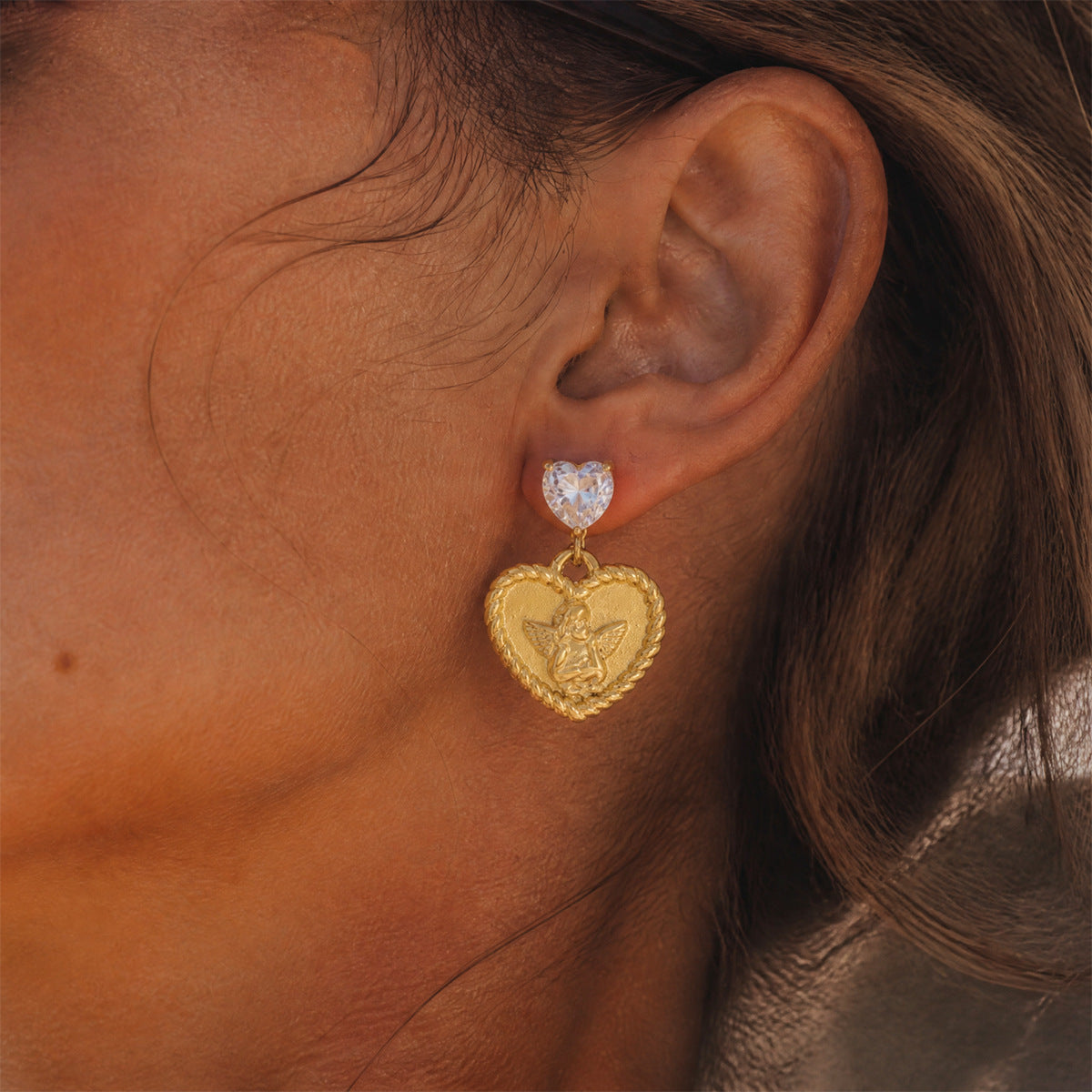 Gold tone angel heart earring shown on the ear
