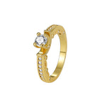 isolated gold plated brass four-prong solitaire ring on white