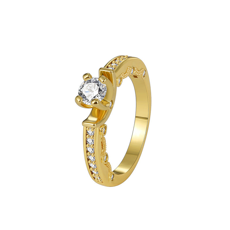 isolated gold plated brass four-prong solitaire ring on white
