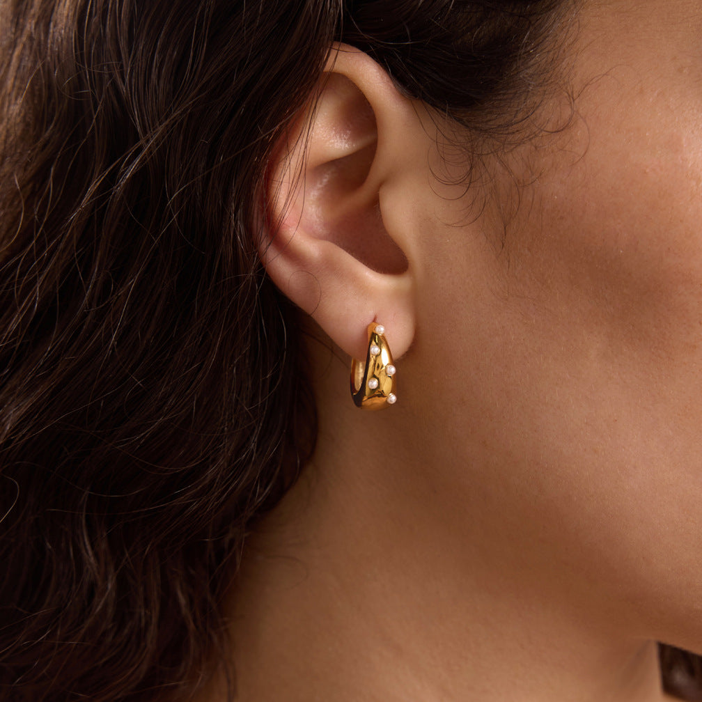 Gold-tone pearl-dotted hoop worn alone on the ear