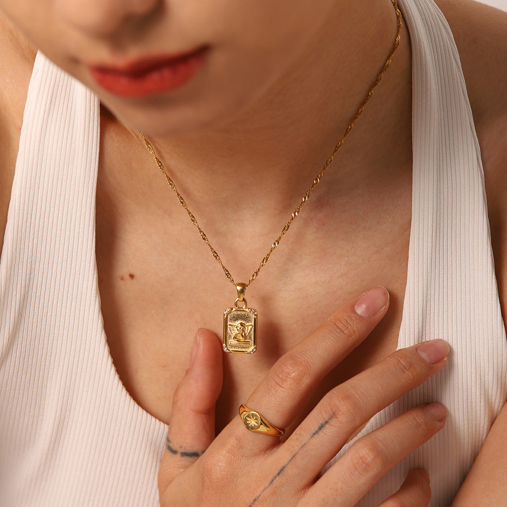 Model wearing a rectangular relief pendant on a gold-tone chain