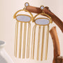 gold plated stainless steel shell chain tassel earrings on natural wood