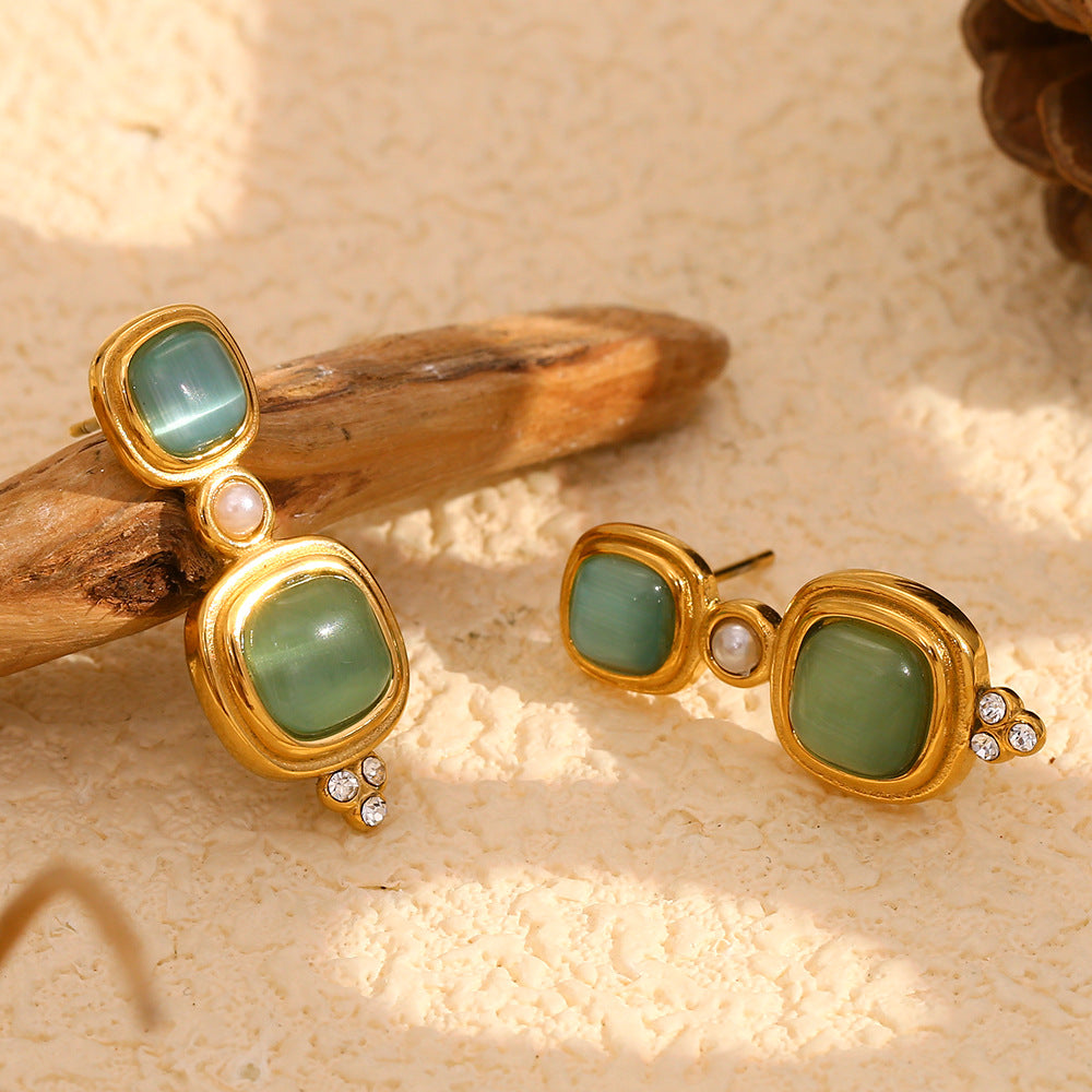 angled view of green cabochon earrings beside natural wood